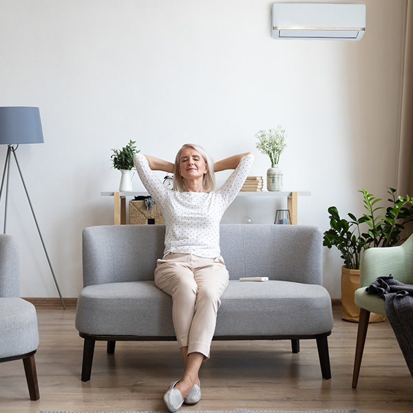 Relaxed older woman sitting on couch in air conditioner room