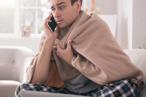 A man with blanket on his back talking on phone